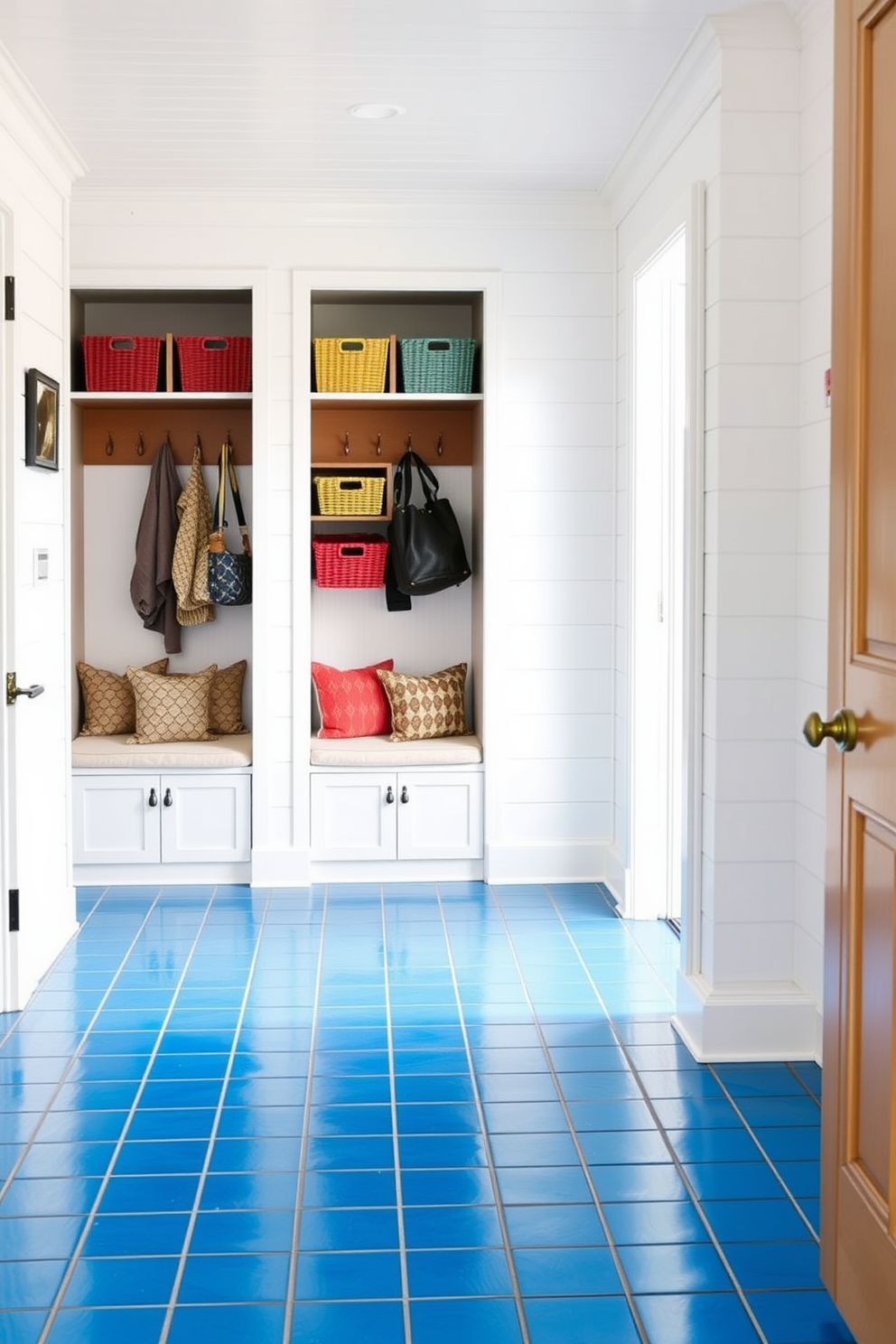 Bright azure tiles cover the floor of a spacious entryway, creating a vibrant and inviting atmosphere. The walls are adorned with white shiplap, providing a crisp contrast to the bold tile color. In the adjacent mudroom, built-in wooden benches with soft cushions offer a comfortable seating area. Storage cubbies above the benches hold colorful baskets for organization, while hooks line the walls for coats and bags.