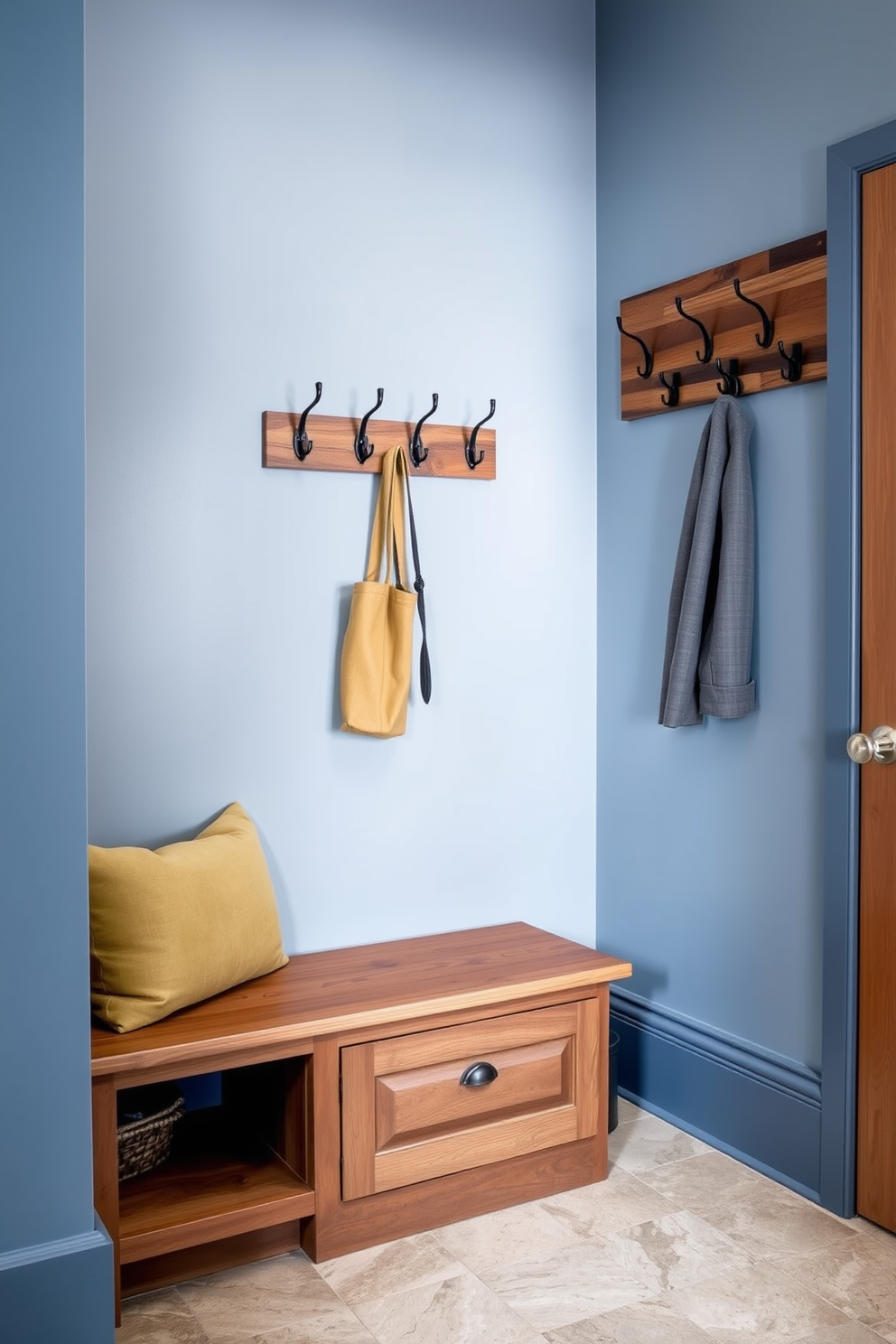 A serene mudroom space featuring muted blue tones complemented by natural wood accents. The walls are painted in a soft blue hue, while a wooden bench with storage underneath provides functionality and warmth. A stylish coat rack made of reclaimed wood is mounted on the wall, adorned with various hooks for convenience. The floor is covered with a durable yet chic tile that mimics the look of natural stone, enhancing the overall aesthetic.