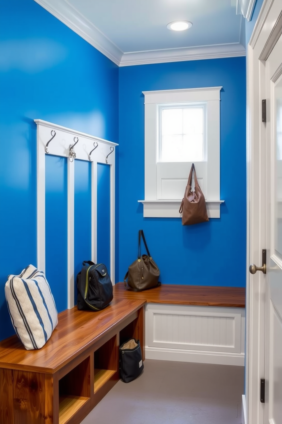 A vibrant mudroom featuring cobalt blue wall paint complemented by crisp white trim. The space includes built-in wooden benches with storage underneath and a series of hooks for hanging coats and bags.