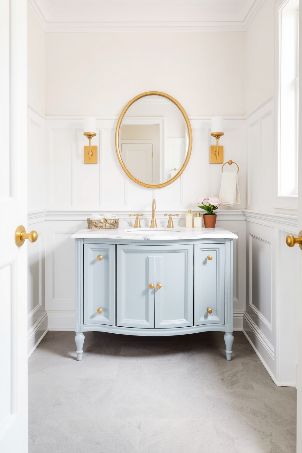 A powder blue vanity with a polished marble top sits elegantly in a chic powder room. The walls are adorned with delicate white wainscoting and the floor is covered in a soft gray tile, creating a serene atmosphere.