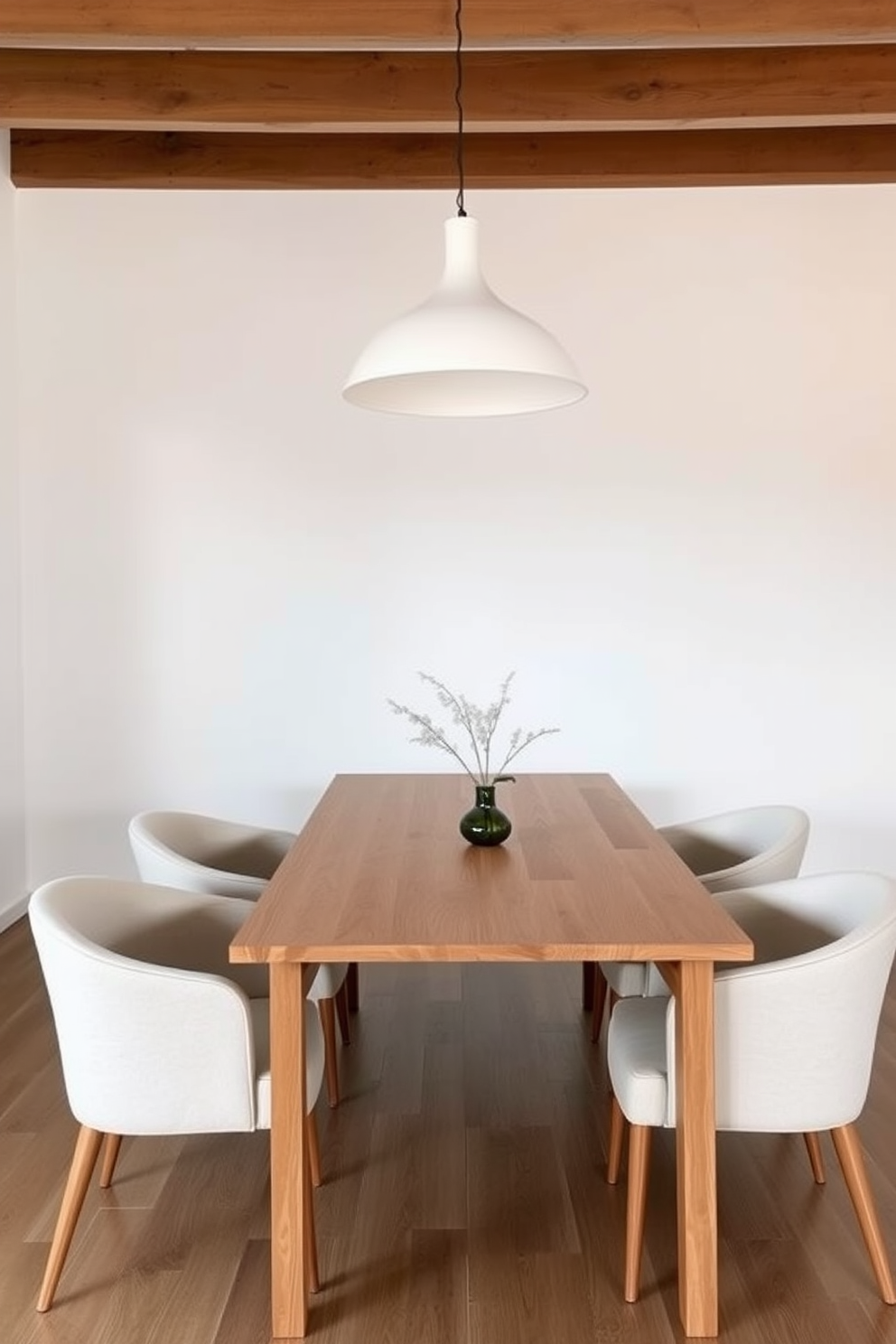 A minimalist Scandinavian dining room features a sleek wooden table with clean lines and a light finish. Surrounding the table are simple yet elegant chairs with soft upholstery in neutral tones, creating a harmonious and inviting atmosphere. The walls are painted in a soft white, enhancing the airy feel of the space. A large pendant light with a minimalist design hangs above the table, providing warm illumination for gatherings.