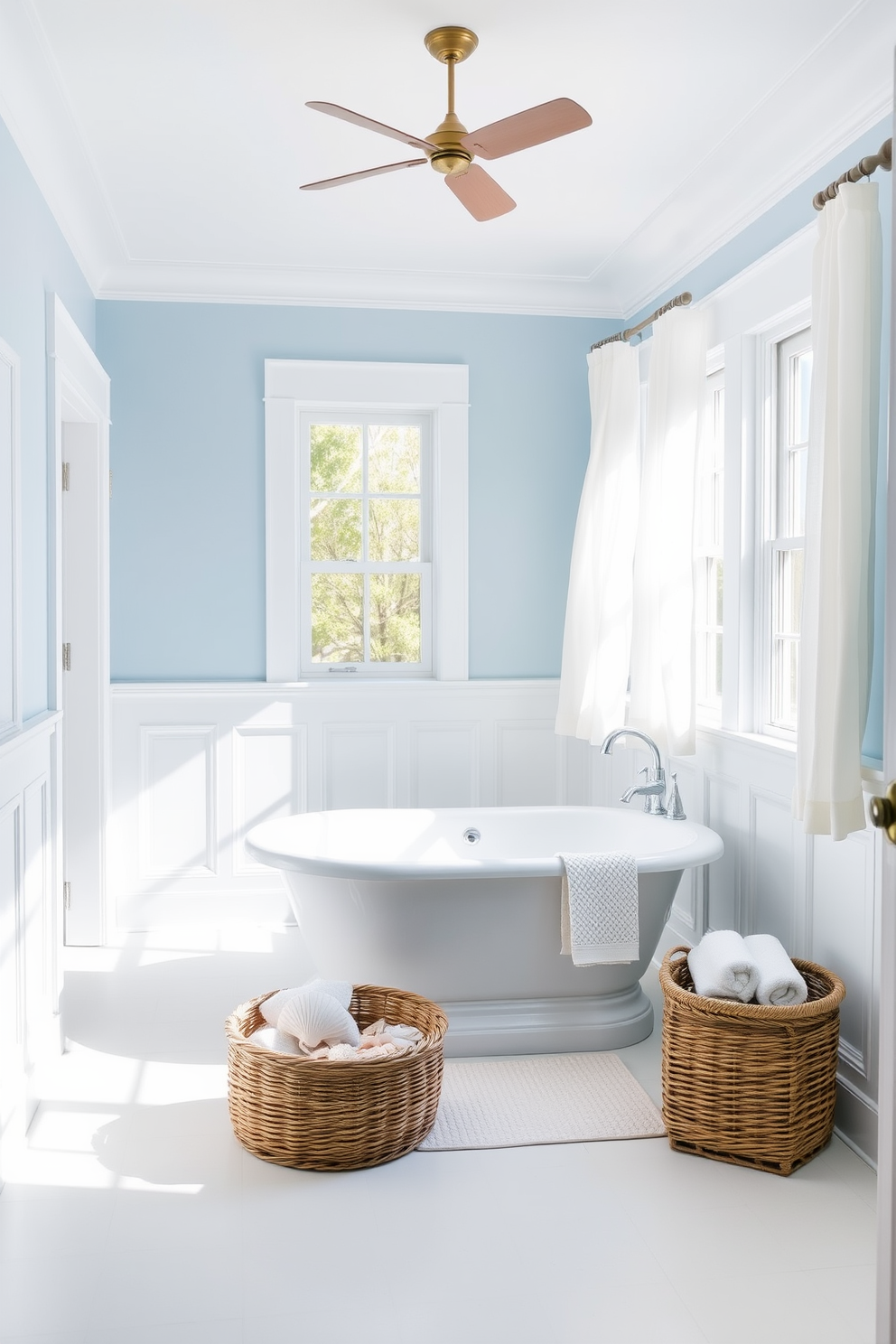 A serene coastal bathroom featuring soft blue hues throughout the space. The walls are painted in a light sky blue, complemented by white wainscoting and natural wood accents. A freestanding soaking tub sits in the center, surrounded by seashell decor and a woven basket for towels. Large windows allow natural light to flood the room, with sheer white curtains gently billowing in the breeze.