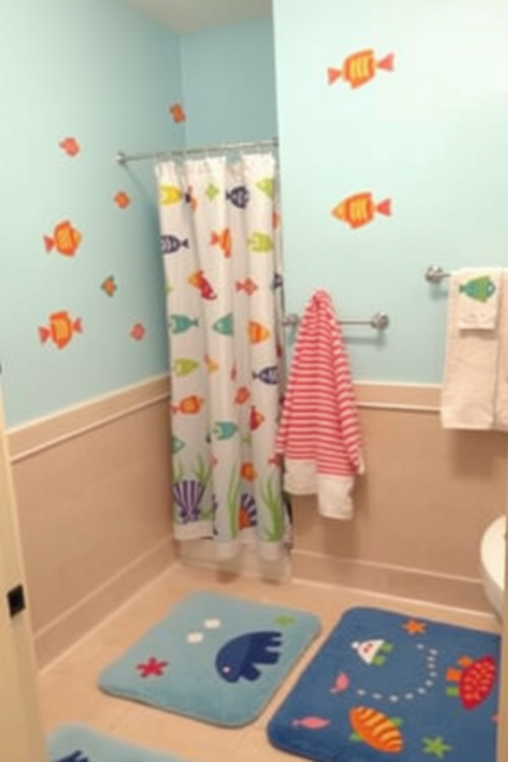 A whimsical kids bathroom design featuring an underwater theme. The walls are painted in a light blue shade with colorful fish decals swimming across the surface. There is a playful shower curtain adorned with sea creatures and matching towels hanging on a rack. The floor is covered with soft, ocean-themed bath mats, creating a fun and inviting atmosphere for children.