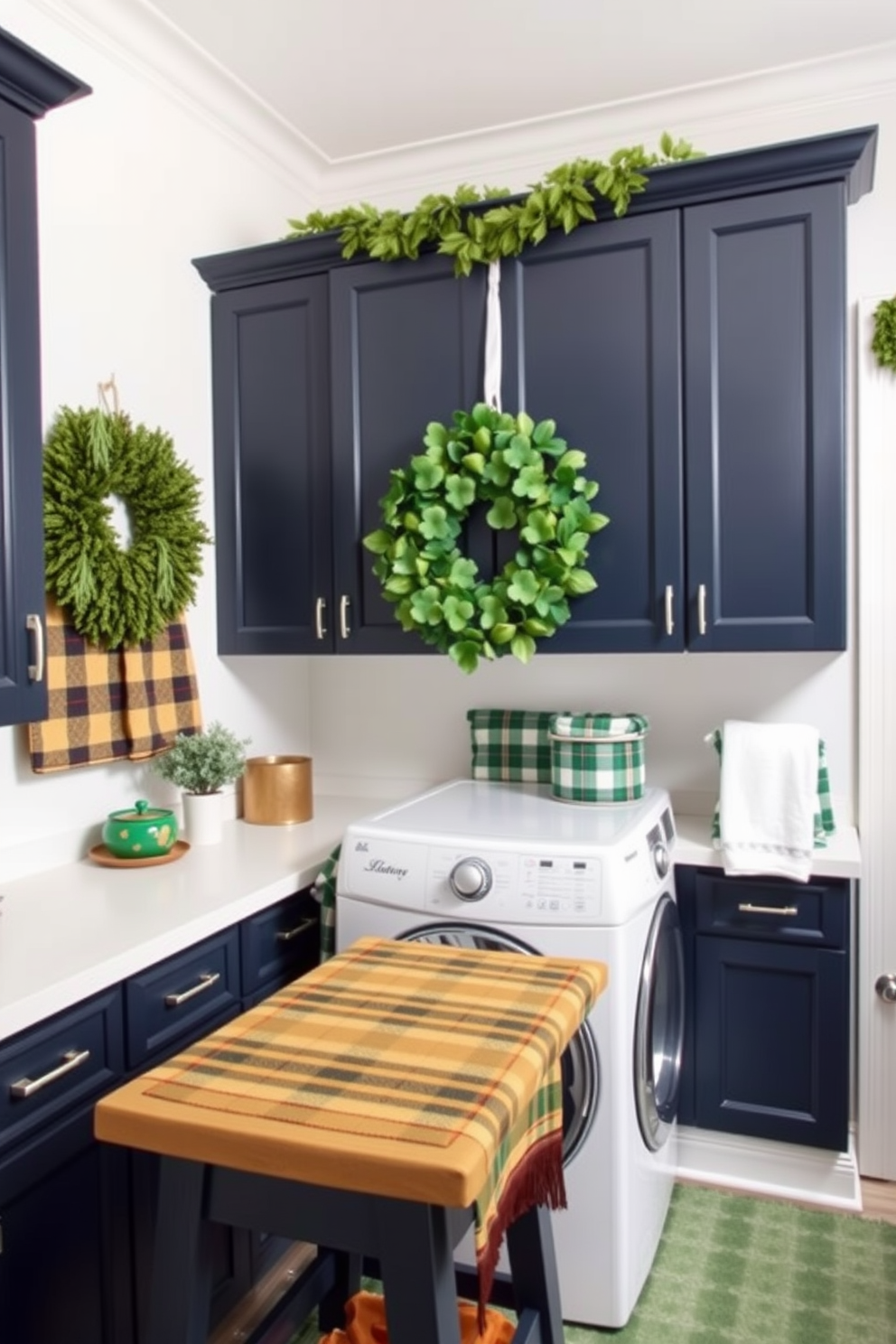 A cozy laundry room featuring plaid patterns in the textiles. The walls are painted a soft white, and the cabinetry is a rich navy blue, creating a fresh and inviting atmosphere. Decorative elements include green and gold accents in honor of St. Patrick's Day. A cheerful wreath made of shamrocks hangs on the door, and a plaid table runner adorns the folding table.
