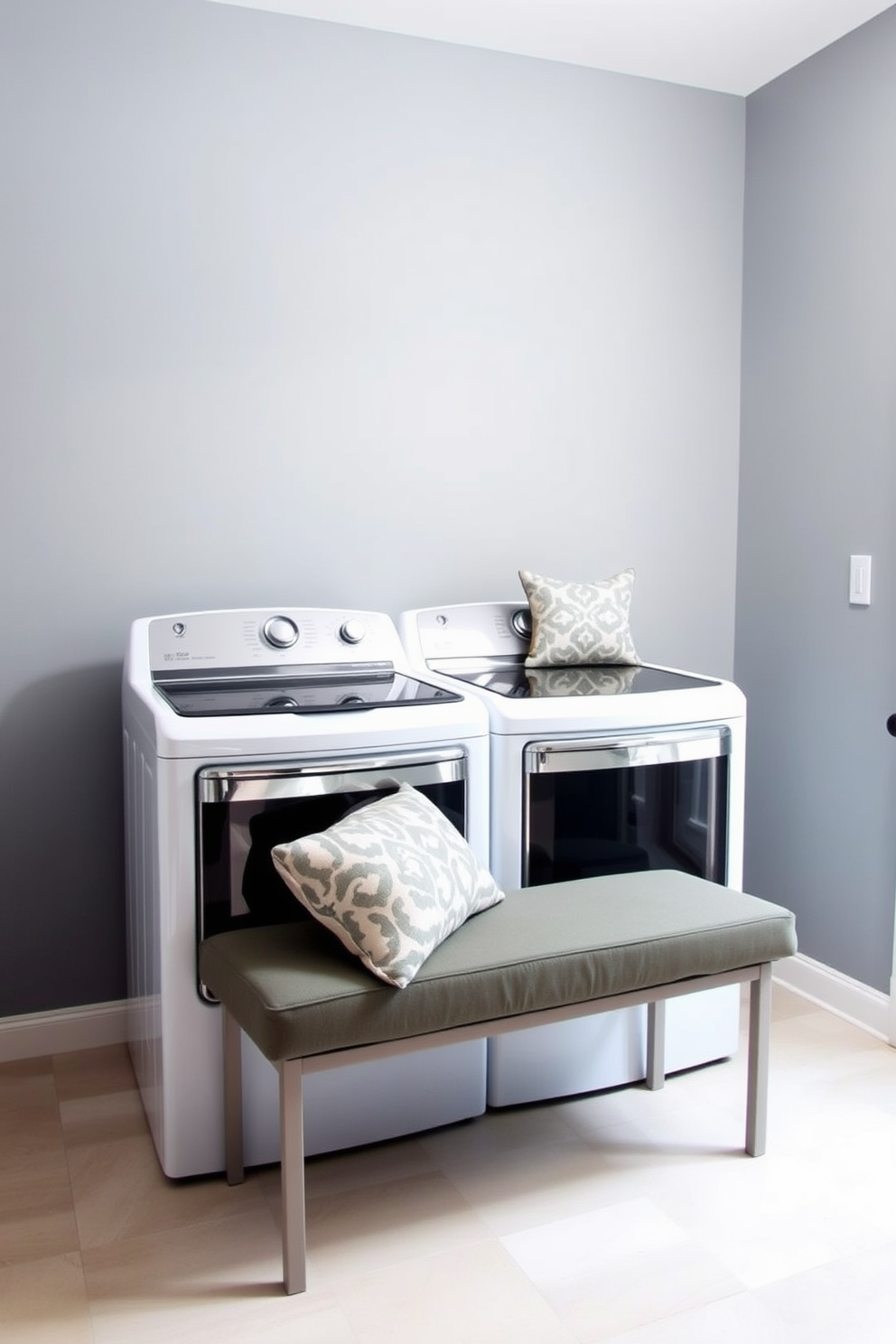 A modern laundry room featuring a top loading washer and dryer set against a backdrop of soft gray walls. A small, cushioned bench is placed near the washer for comfort, adorned with decorative pillows to enhance the inviting atmosphere.