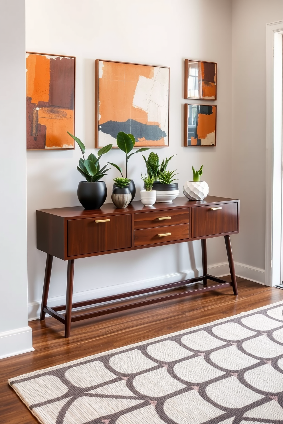 A stylish foyer featuring a sleek console table made of dark wood. On the table, modern pots with various greenery add a touch of life, complementing the Mid Century Modern aesthetic. The walls are adorned with abstract art pieces that reflect warm tones. A geometric area rug anchors the space, enhancing the inviting atmosphere of the foyer.