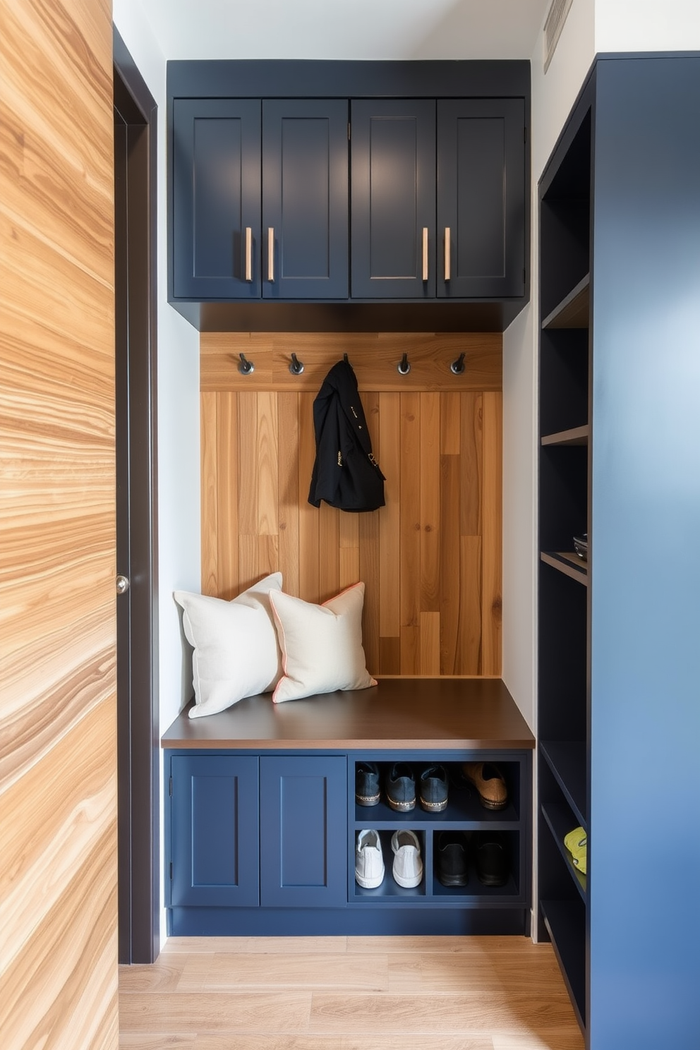 Custom cabinetry for tailored storage. The cabinetry features a blend of deep navy blue and warm wood tones, providing both functionality and style. Modern mudroom design ideas. The space includes a built-in bench with plush cushions and hooks for coats, complemented by sleek storage cubbies for shoes and bags.
