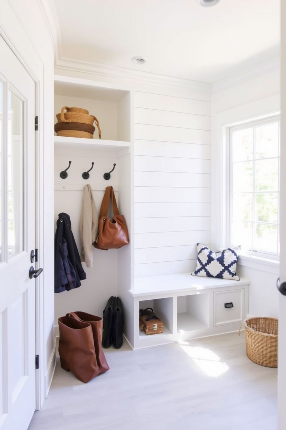 A bright white shiplap accent wall creates a clean and inviting atmosphere in the mudroom. The space features built-in cubbies for storage with stylish hooks for coats and bags, complemented by a bench for easy seating. Natural light floods the room through a large window, enhancing the brightness of the white shiplap. A durable yet chic floor material, such as tile or luxury vinyl, adds practicality while maintaining the modern aesthetic.