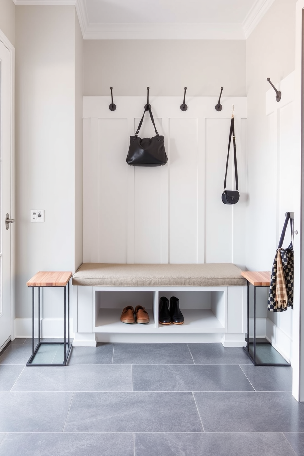 A contemporary bench is positioned against the wall, featuring a sleek design with clean lines and upholstered seating for comfort. Flanking the bench are two stylish side tables, crafted from natural wood with minimalist metal accents, providing functional space for shoes and bags. The mudroom is designed with practicality in mind, featuring a built-in bench that offers ample storage underneath for outdoor gear. The walls are adorned with hooks for coats and bags, and the flooring is a durable tile that complements the overall aesthetic.
