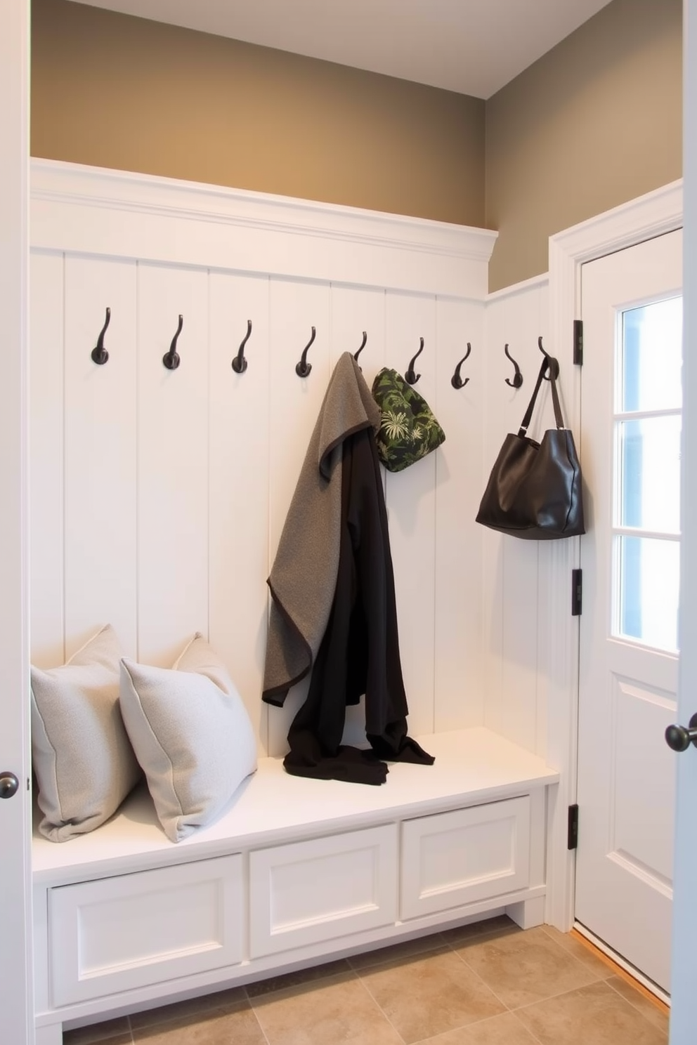 A cozy mudroom features a corner bench with custom cushions in a soft fabric. The walls are adorned with hooks for coats and bags, and the floor is tiled for easy cleaning.
