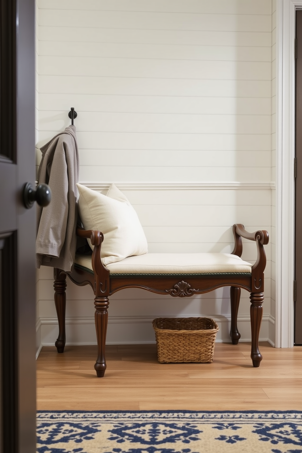 An elegant bench with decorative trim is positioned in a stylish mudroom. The bench features a soft upholstered seat and intricate woodwork, complemented by a backdrop of shiplap walls painted in a calming neutral tone.
