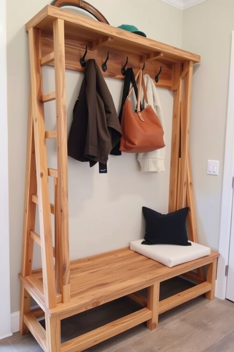 A functional mudroom features a ladder-style bench made of reclaimed wood with a natural finish. Above the bench, there is a hanging space with hooks for coats and bags, complemented by a soft cushion for seating.