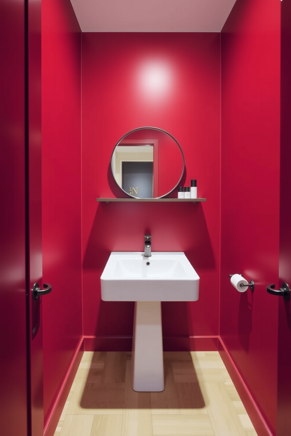 A minimalist red powder room features sleek lines and a bold color palette. The walls are painted in a vibrant red, complemented by a simple white pedestal sink and a round mirror with a thin black frame. A floating shelf displays a few carefully chosen decorative items, maintaining the room's uncluttered aesthetic. The flooring consists of light wood planks, providing a warm contrast to the striking red walls.