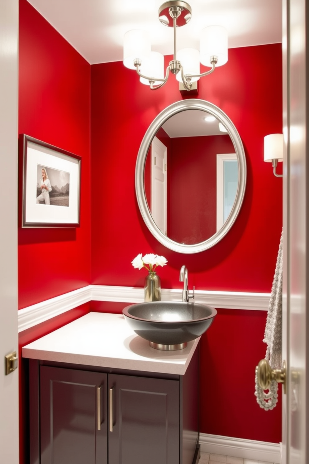 A sophisticated powder room featuring a striking red and gray color palette. The walls are painted in a deep red hue, complemented by elegant gray accents in the decor and fixtures. A sleek gray vanity with a white countertop sits against the wall, adorned with a modern vessel sink. Above the vanity, a large round mirror with a silver frame reflects the stylish lighting fixtures that add a touch of glamour.