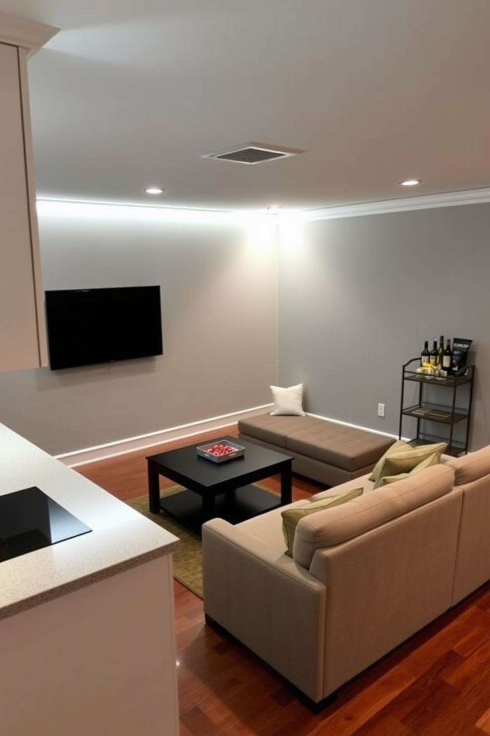 A cozy small game room features under-cabinet lighting that illuminates the sleek countertops and creates a warm ambiance. The walls are painted in a soft gray, and a plush sectional sofa is arranged around a coffee table for comfort during game nights. A wall-mounted TV is positioned for optimal viewing, while a small bar cart is stocked with snacks and drinks. The flooring is a rich hardwood, enhancing the inviting atmosphere of the space.