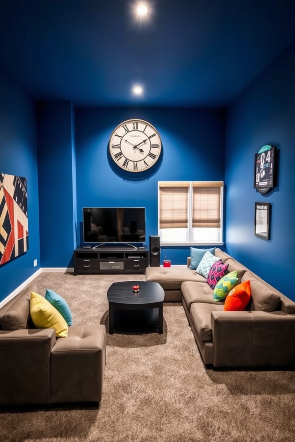 A vibrant game room designed for entertainment and relaxation. The walls are painted in a bold blue hue, and the floor is covered with a plush gray carpet. In the center, a large sectional sofa is adorned with colorful throw pillows, facing a sleek entertainment unit. A gaming-themed clock hangs prominently on the wall, adding a unique touch to the space.