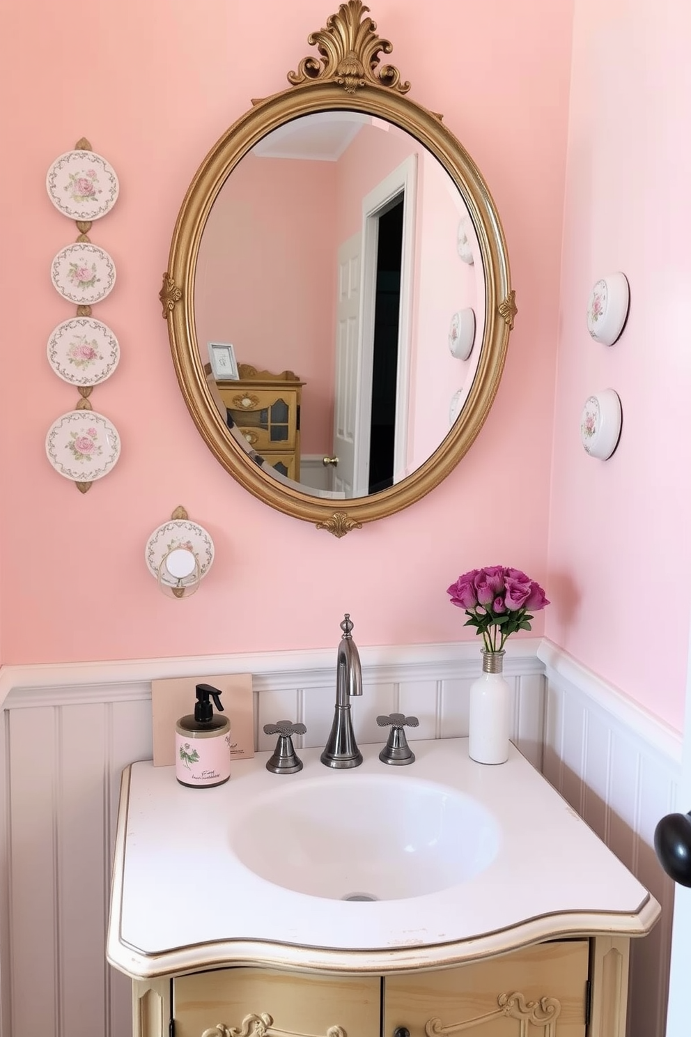 Charming wall-mounted soap dishes create an inviting atmosphere in a vintage powder room. The soap dishes are adorned with intricate floral patterns and soft pastel colors, complementing the aged wooden vanity below. The walls are painted in a soft blush hue, accented by white wainscoting that adds depth and character. A round mirror with an ornate gold frame hangs above the vanity, reflecting the delicate details of the room.