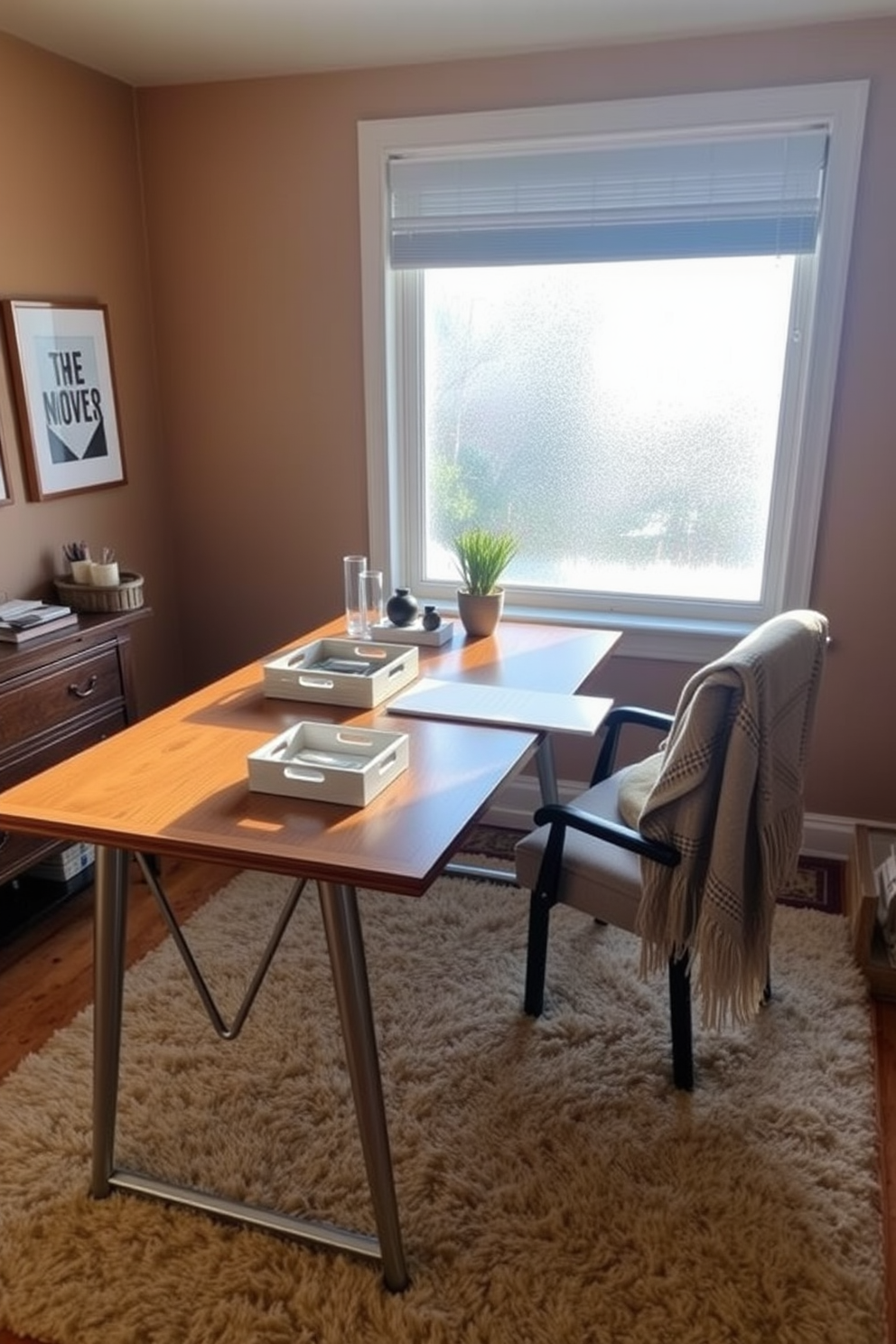 A cozy winter home office features a large wooden desk positioned in front of a frosted window, allowing soft natural light to fill the space. On the desk, decorative trays in a mix of textures and colors organize stationery and personal items, adding both functionality and style. The walls are painted a warm, inviting shade, accented by a plush area rug that complements the overall decor. A comfortable chair with a cozy throw draped over it invites creativity and productivity, while a small potted plant adds a touch of greenery to the workspace.